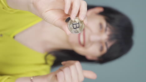 Vertical-video-of-Woman-holding-bitcoin-and-showing-it.